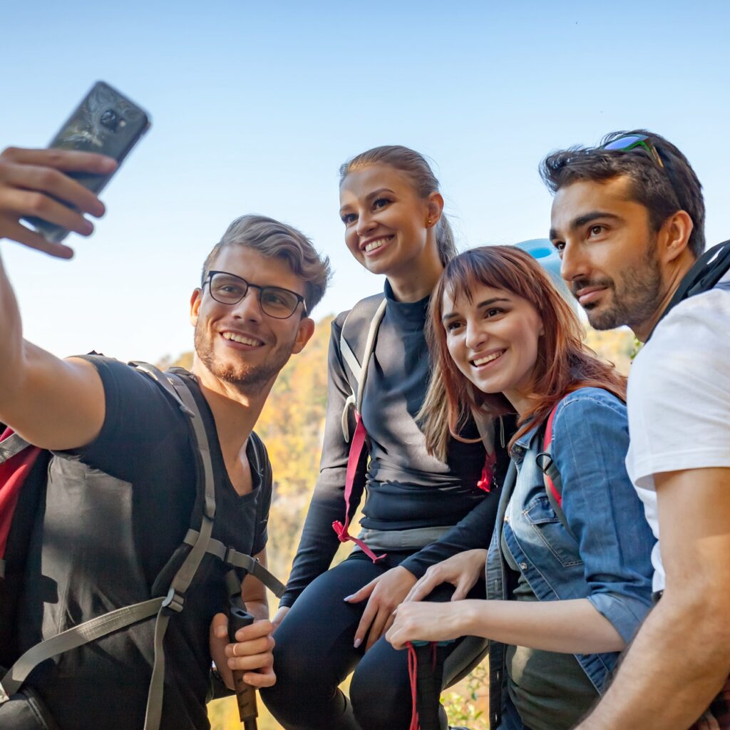 Friends with backpacks making selfie photo together at the peak of mount, travel and tourism concept